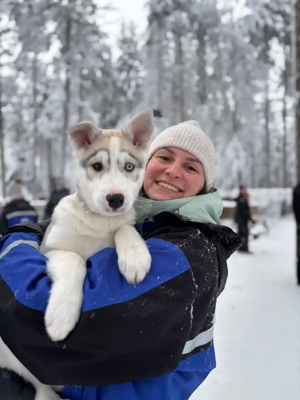 Person holding husky puppy outdoors in winter