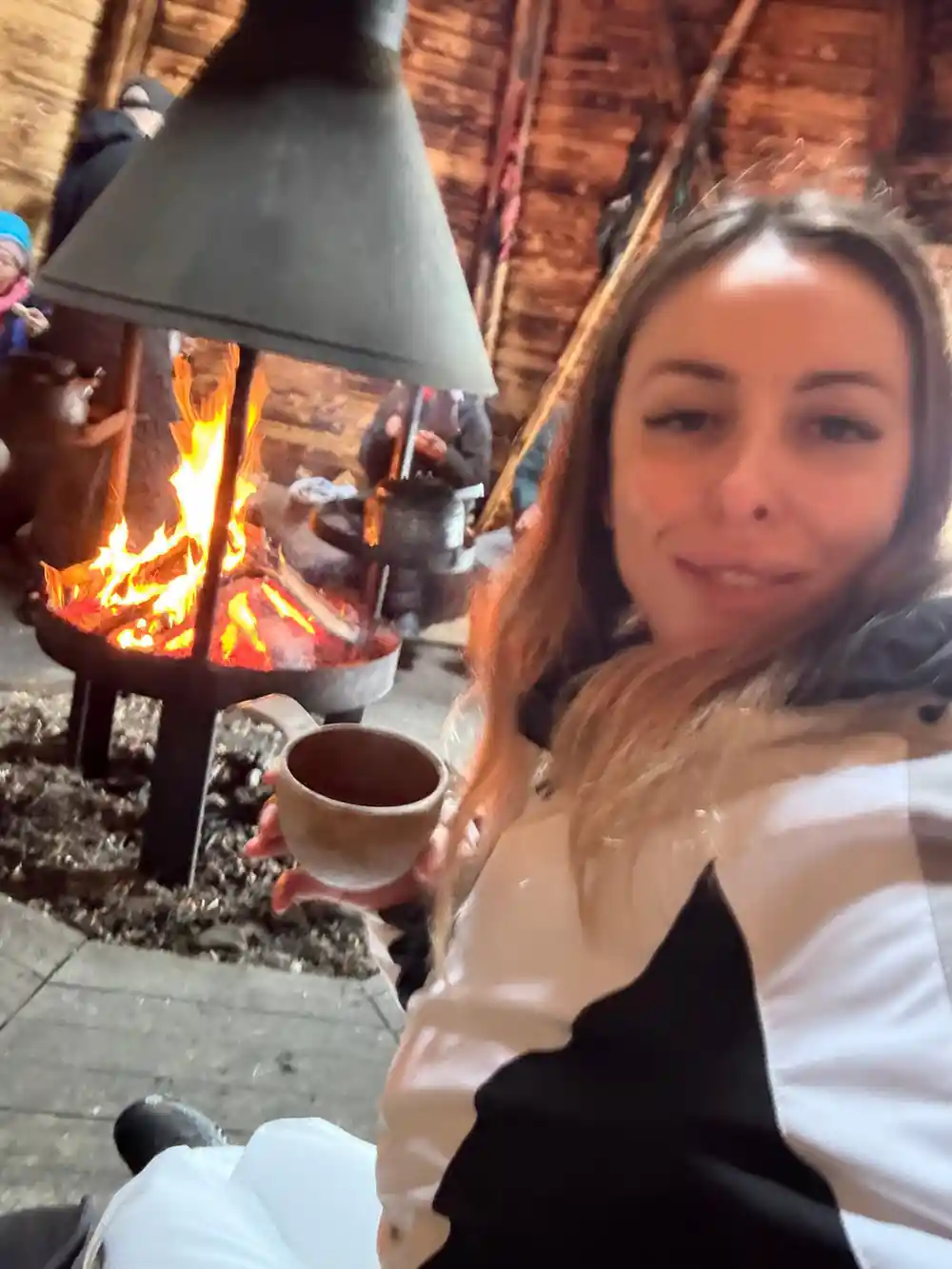 Woman by fireplace with hot drink at night